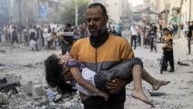 رجل فلسطيني يحمل طفلة مصابة في غزة (ياسر قديح/ فرانس برس)