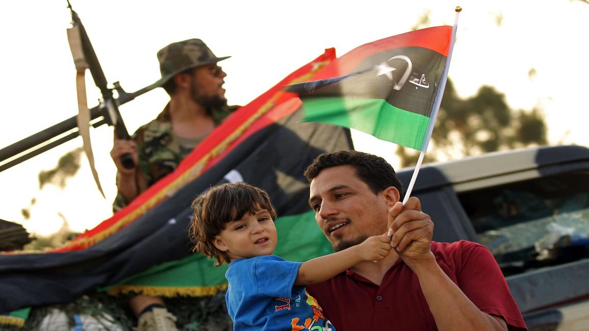 طفل ليبي مع والده وخلفهما آلية عسكرية- فرانس برس