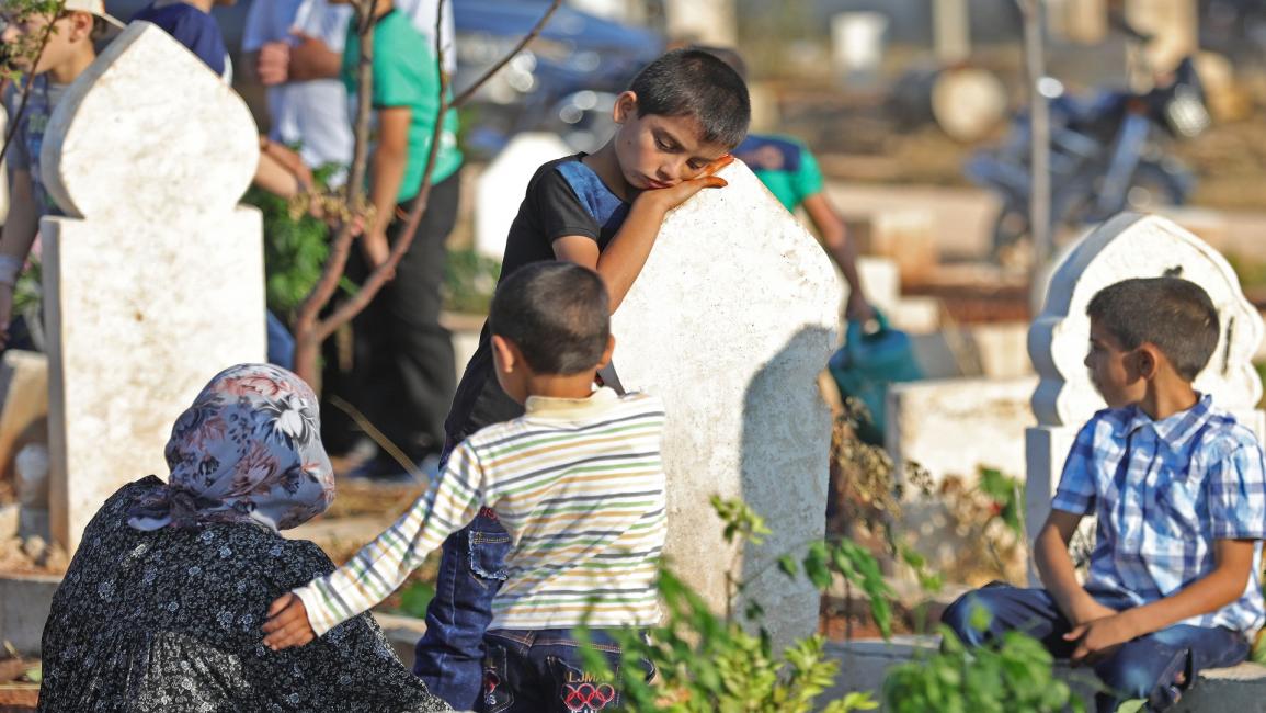 طفل سوري أمام قبر في بنّش- فرانس برس