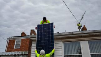 الطاقة النظيفة في الولايات المتحدة، عاملان يركبّان ألواحاً شمسية على منزل في واشنطن، 23 فبراير 2022 (روب هيل/Getty)