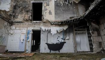 لوحة لرجل يستحم على جدار منزل مدمر بالكامل (جليب جارانيش/رويترز)