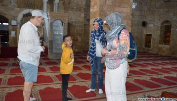 الطفل الفلسطيني عبد الرحمن فران مع سياح في صيدا (العربي الجديد)