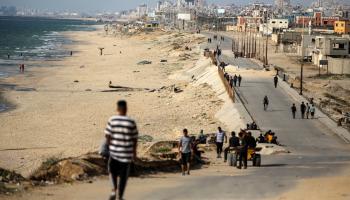 فلسطينيون يسيرون بالقرب من شاطئ البحر في قطاع غزة، 18 مايو 2024 (مجدي فتحي/ Getty)
