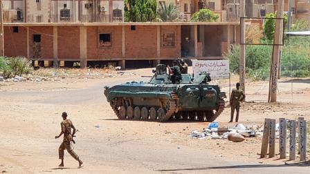 جنود من الجيش السوداني يسيرون بالقرب من مركبات مدرعة متمركزة في أحد شوارع جنوب الخرطوم، 6 مايو 2023 (Getty)