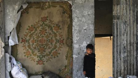 طفل فلسطيني يقف فوق أنقاض منزله الذي دمّره العدوان، رفح، 22 أيار/ مايو 2024 (Getty)