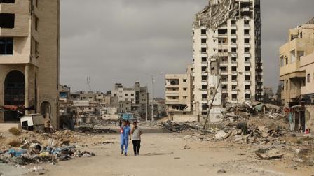 فلسطينيون يسيرون وسط الأنقاض في غزة، 27 مايو 2024 (الأناضول)