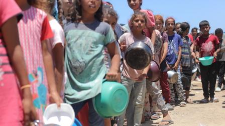 أطفال ينتظرون في الطابور للحصول على طعام في دير البلح، 28 مايو 2024(الأناضول)